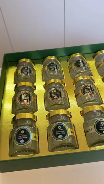 Hộp xanh mở nắp với 15 hũ yến chưng Hoàng Kim nắp vàng, tem đen vàng